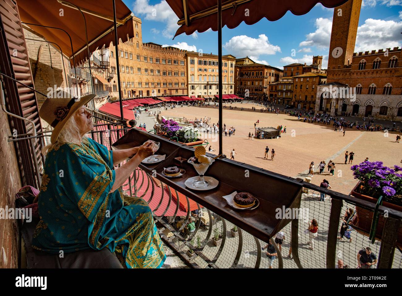 Siena Toscana Italia settembre 2023 la modella rilasciata donna gode di gelato e torta guardando la Piazza del campo e la Torre della Mangia (Torre de Foto Stock