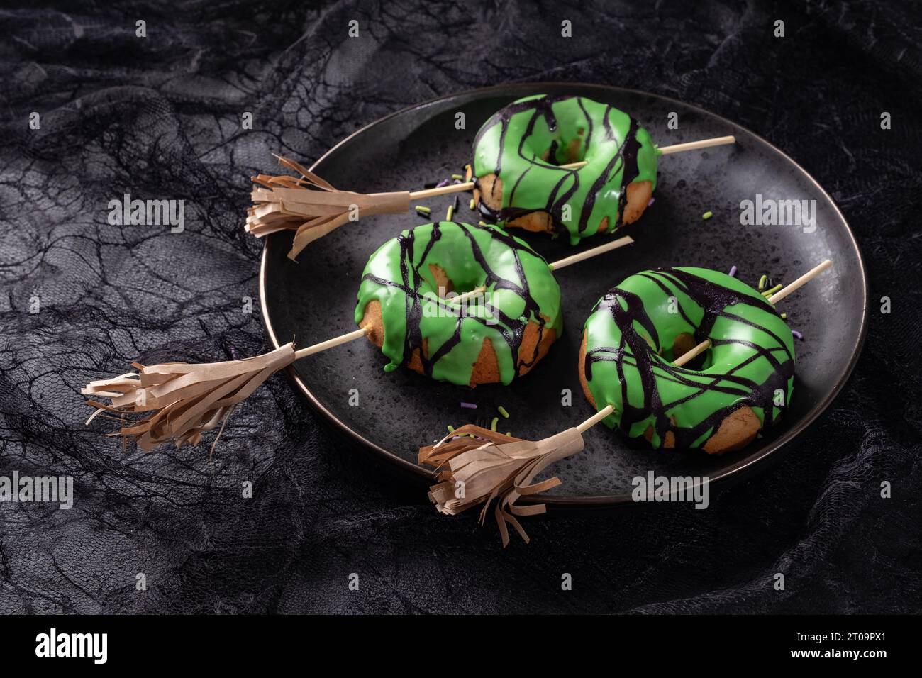 Ciambella di Halloween con glassa verde e scopa da strega. Scherzetto o scherzetto di Halloween. Foto Stock