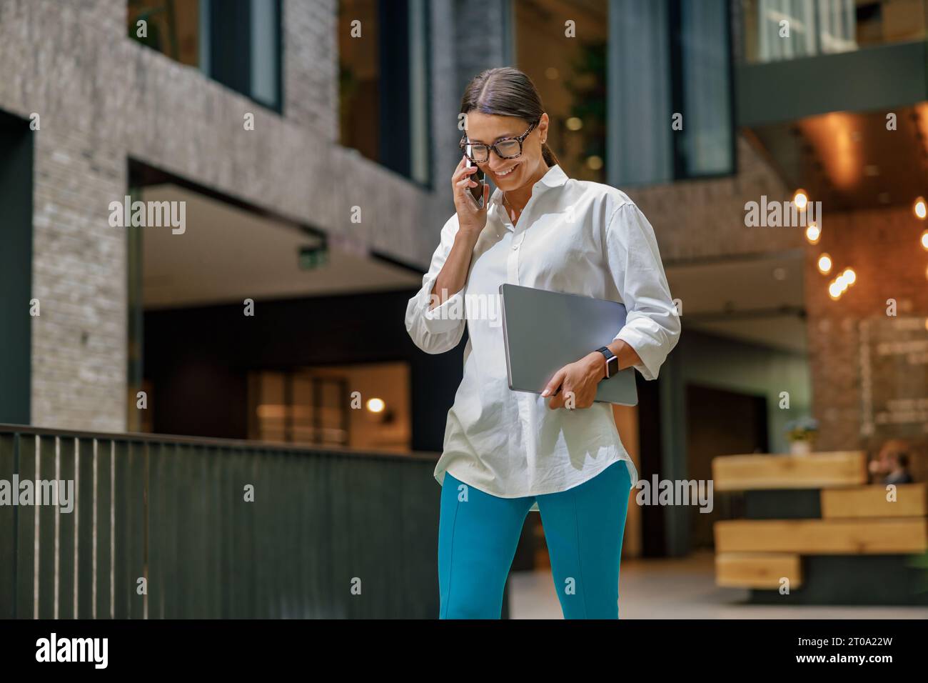 Donna allegra imprenditrice che parla al telefono con il cliente mentre lavora in un ufficio moderno Foto Stock