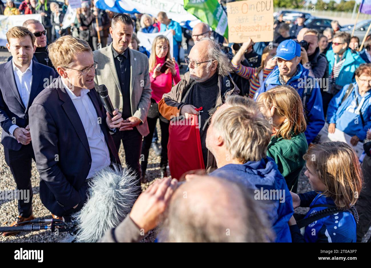 05 ottobre 2023, Schleswig-Holstein, Neumünster: Daniel Günther (CDU), Ministro Presidente dello Schleswig-Holstein, parla con i manifestanti del Fridays for Future, BUND SH, Diving Association e Friends of Nature Association for the Baltic Sea National Park, di fronte all'assemblea rappresentativa del CDU Schleswig-Holstein, di fronte all'edificio delle conferenze sulla creazione di un Parco Nazionale del Mar Baltico. Foto: Axel Heimken/dpa Foto Stock