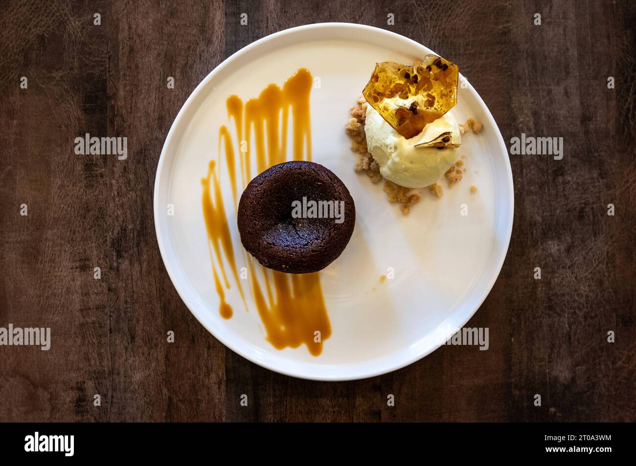 Scatto ad angolo elevato di una torta di lava al cioccolato fondente, un cucchiaio di ghiaccio alla vaniglia, un cracker dolce e una salsa al caramello, Bruxelles, belgio Foto Stock