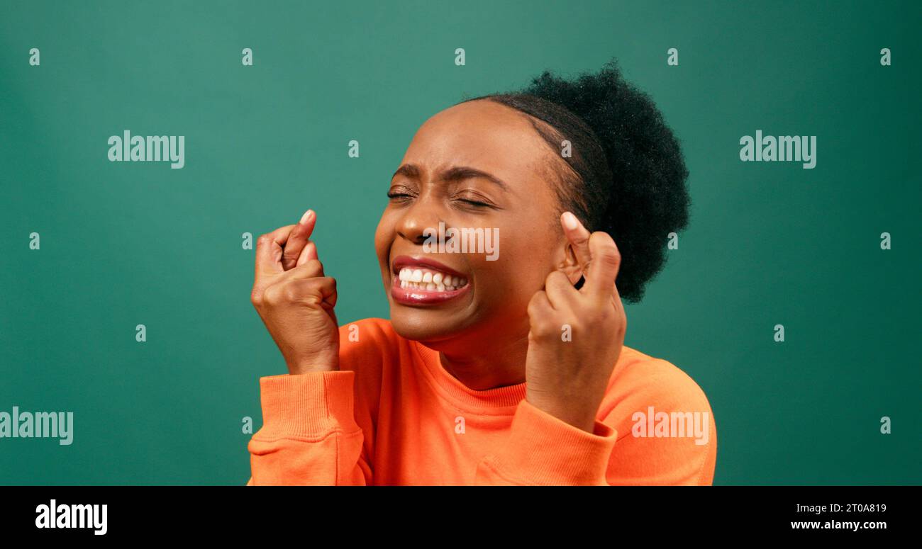 Bella giovane donna con le dita incrociate, desiderosa e sperante, studio verde Foto Stock