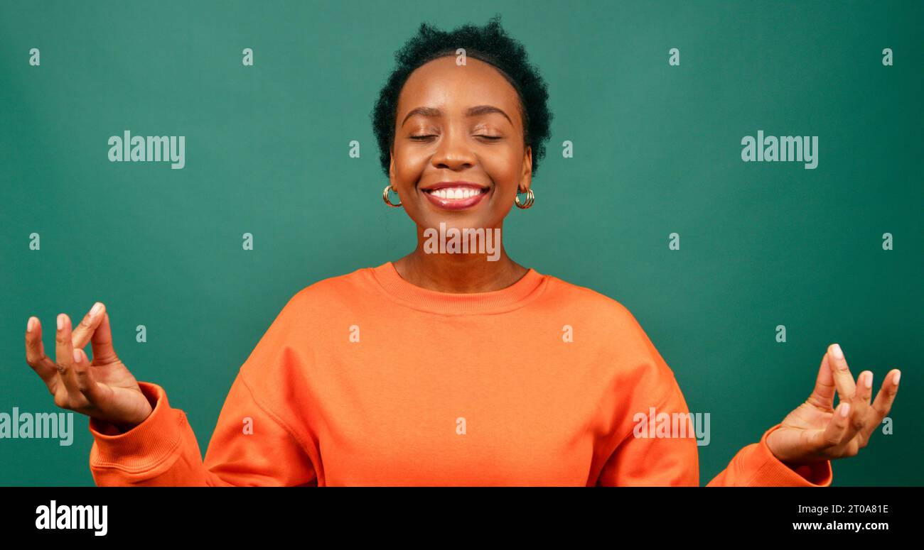 La bella donna Nera respira e medita, sentendosi felice, studio verde Foto Stock