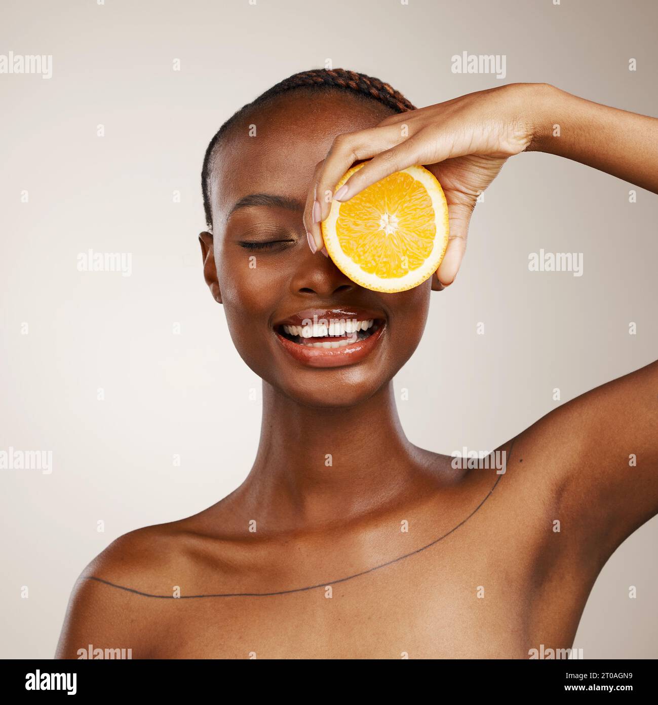 Donna nera, frutti d'arancia e bellezza in studio per la vitamina c, cosmetici vegani e trattamento viso su sfondo marrone. Modello felice, agrumi e nutrizione per Foto Stock