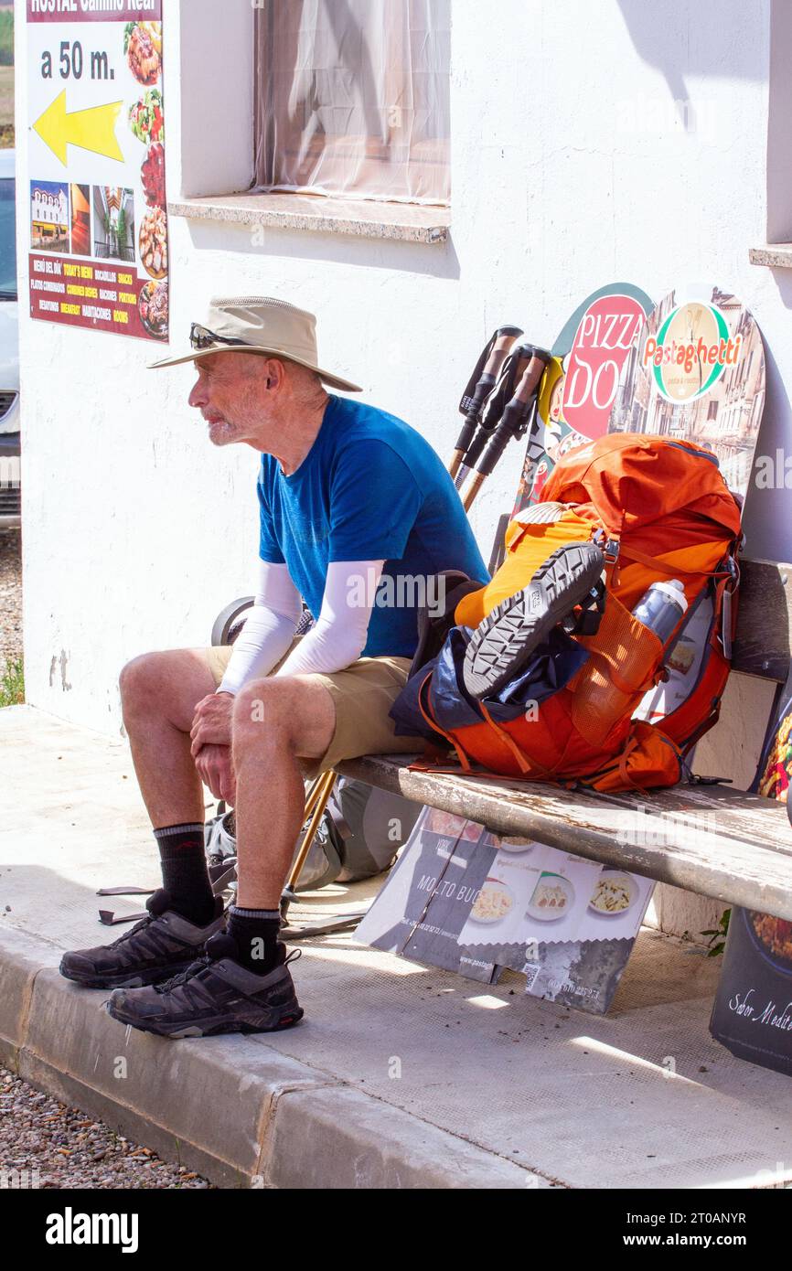 Pellegrino che si rilassa su una panchina nel villaggio spagnolo di Calzadilla de la Cueza con una pausa pranzo mentre cammini de Santiago lungo il cammino di San Giacomo Foto Stock