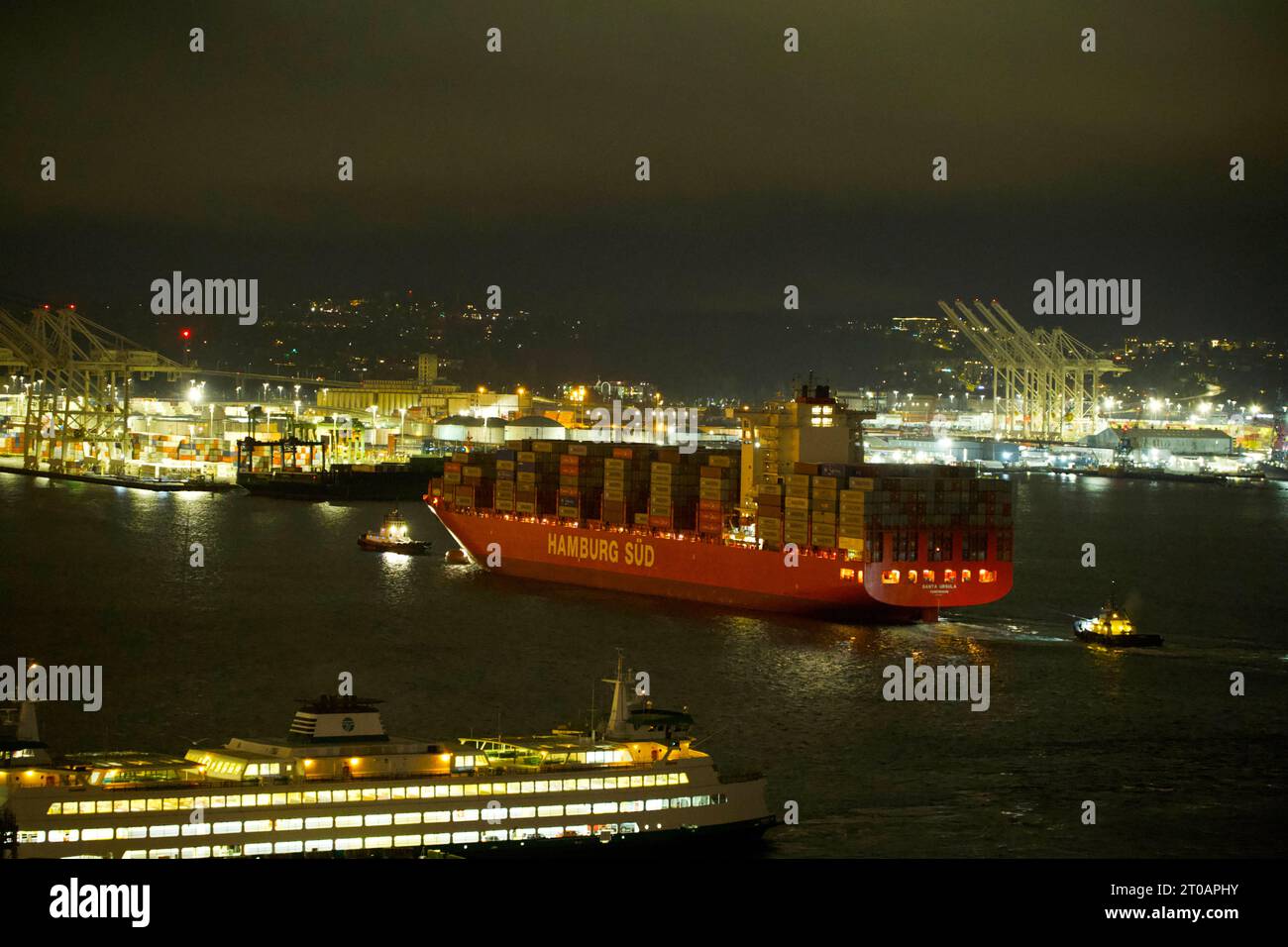 Attracchi per navi portacontainer la mattina presto nel porto di Seattle con l'aiuto di diversi rimorchiatori Foto Stock
