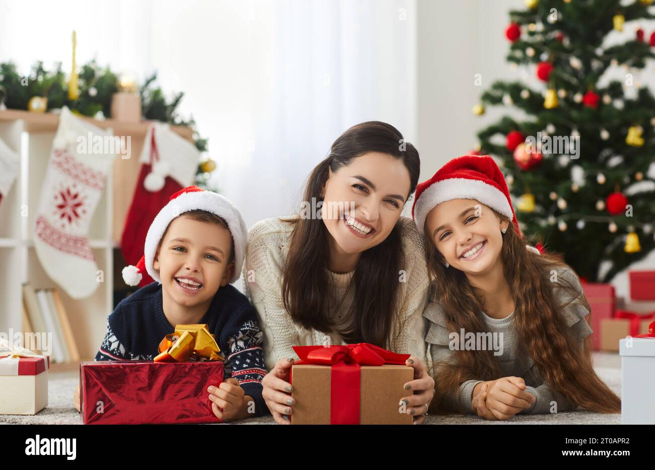 Ritratto di madre felice e bambini piccoli con i loro regali di Natale a casa Foto Stock