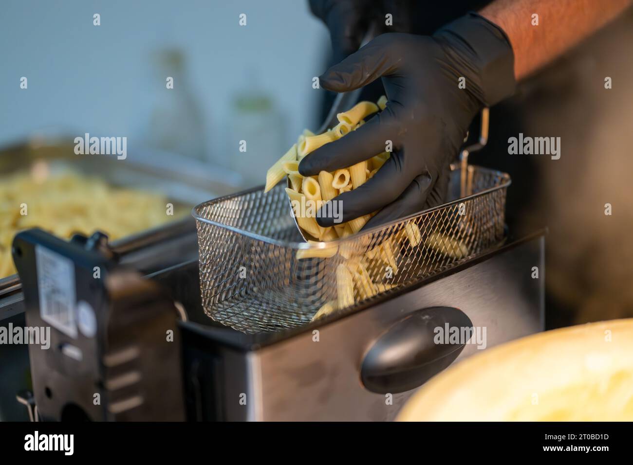 , Food, Deutschland, 02.10.2023, ein paar Hände mit schwarzen Handschuhen bereiten ein Pastagericht zu. SIE legen die Pasta sorgfältig in einen Metal Foto Stock