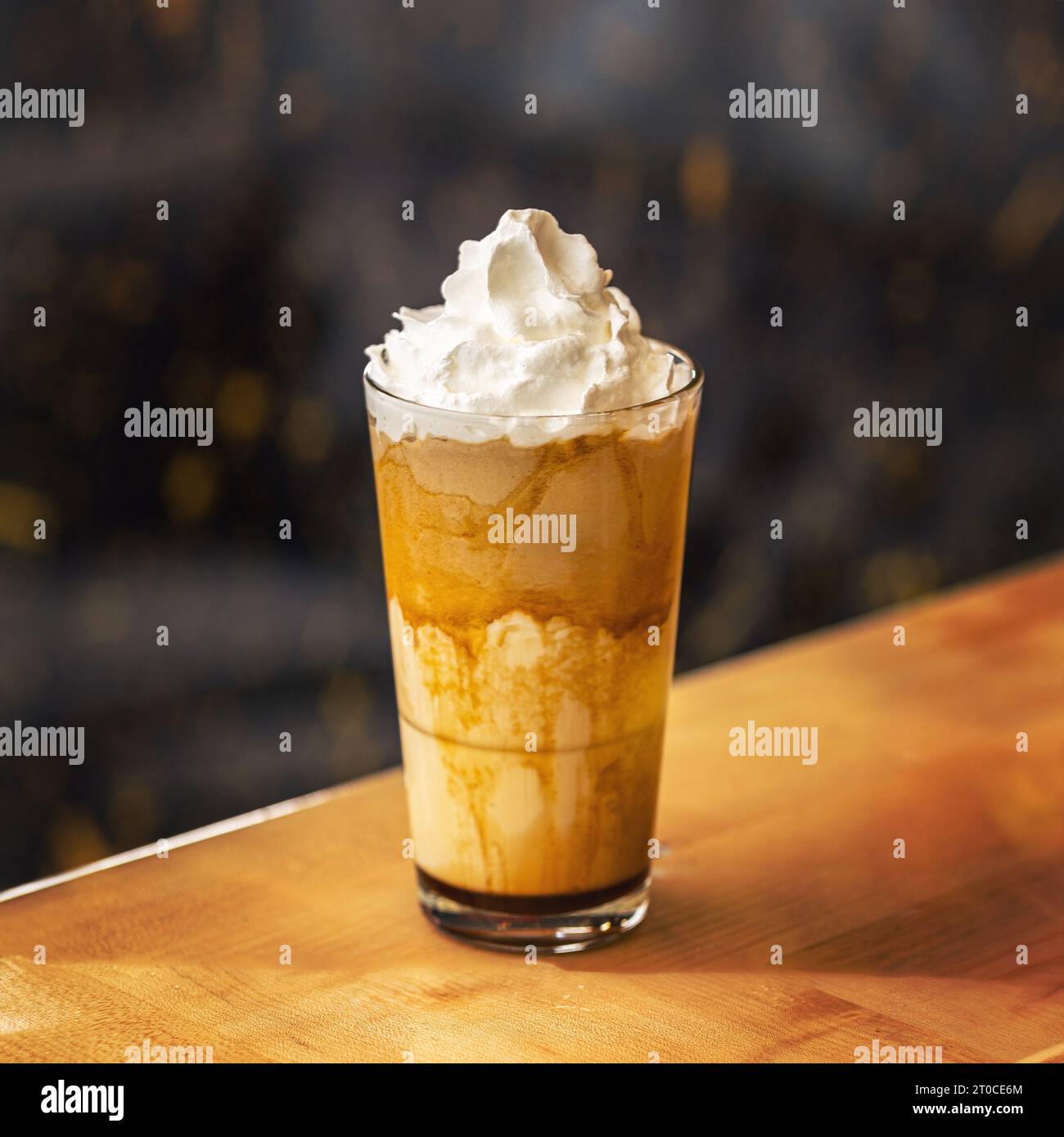 Caffè al caramello in un bicchiere alto con sciroppo e panna montata. Foto Stock