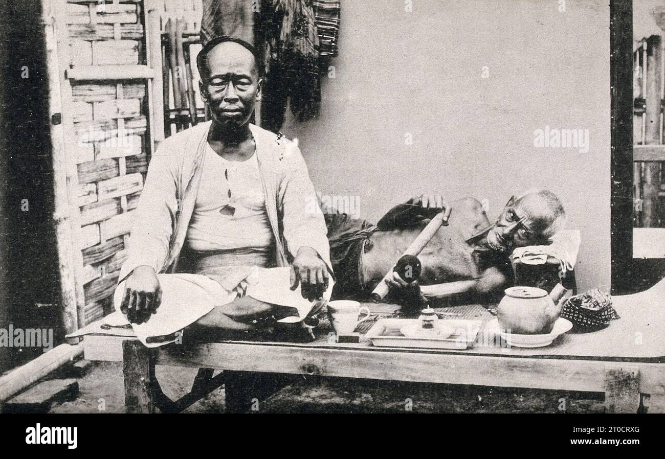 Zwei Opiumraucher, einer liegend, der andere sitzend. Fotografische Postkarte, CA. 1930, Sri Lanka / due fumatori di oppio, uno sdraiato, l'altro seduto. Cartolina fotografica, CA. 1930, Sri Lanka, Historisch, digital restaurierte Reproduktion von einer Vorlage aus dem 19. Jahrhundert Foto Stock