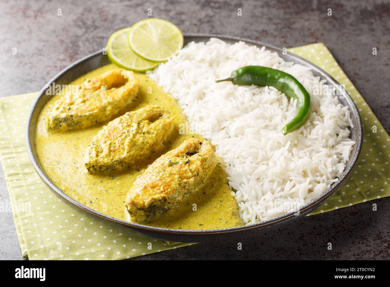 Pesce di Hilsa in salsa di senape o salsa Shorshe Ilish servito con primo piano di riso bianco sul piatto sul tavolo. Orizzontale Foto Stock