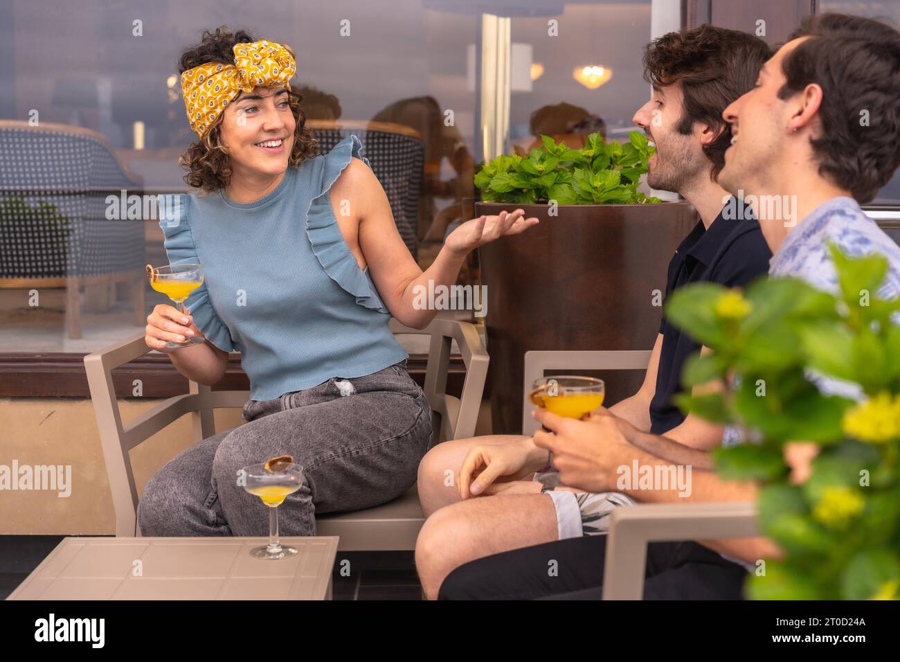 Amici che trascorrono del tempo insieme in vacanza bevendo cocktail e chiacchierando all'aperto Foto Stock