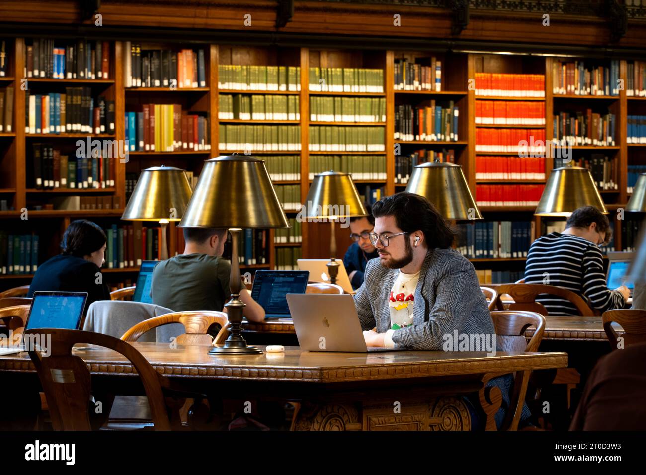 NEW YORK, USA - 18 SETTEMBRE 2023. Uno studente adulto maturo che cerca e impara in una biblioteca universitaria con libri e computer portatile Foto Stock