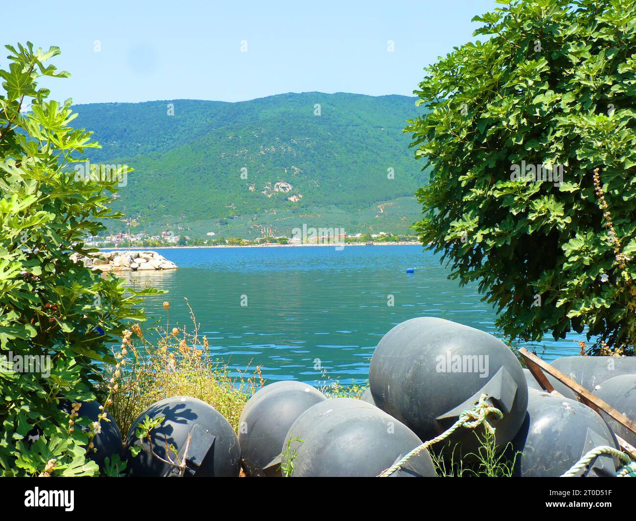 Tranquilla scena all'aperto con profonde acque blu-verdi, boe e lussureggianti Green Mountains in una giornata di sole Foto Stock