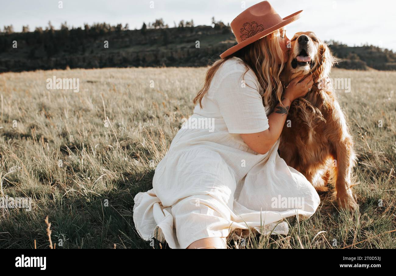 La donna con vestito bianco bacia un cane sorridente Foto Stock