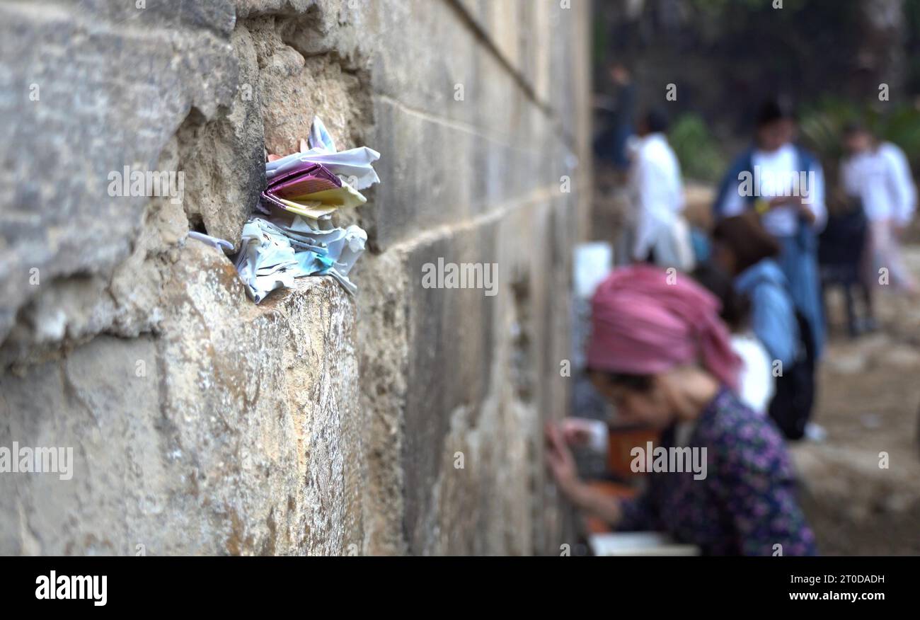 Frammenti di carta contenenti preghiere incastrate nelle fessure del muro occidentale fuori dalla Tomba dei Patriarchi, noti agli ebrei con il suo nome biblico Grotta di Machpelah e ai musulmani come al-Haram al-Ibrahimi, un sito che si crede sia il luogo di riposo finale del profeta Abramo, figura sacra per ebrei e musulmani, situato nel cuore della città vecchia di Hebron, in Israele. Foto Stock