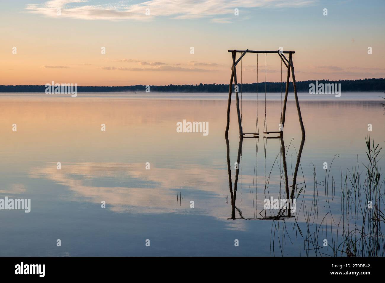 Vista panoramica sulla romantica alba sul Lago bianco con altalena in legno nella regione di Rivne, Ucraina. Foto Stock