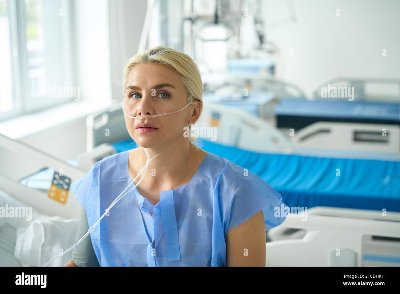 Bella femmina siede su un letto d'ospedale in terapia intensiva Foto Stock