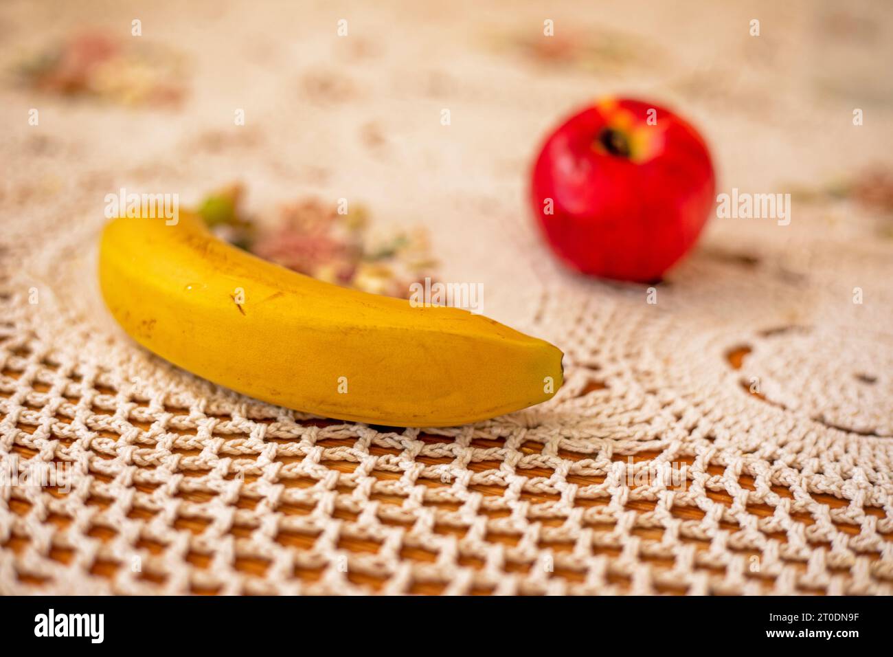 banana gialla matura sul tavolo accanto alla mela Foto Stock