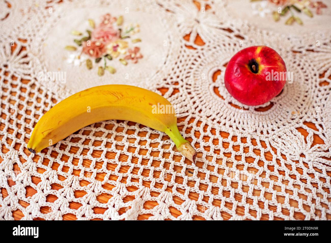 banana gialla matura sul tavolo accanto alla mela Foto Stock
