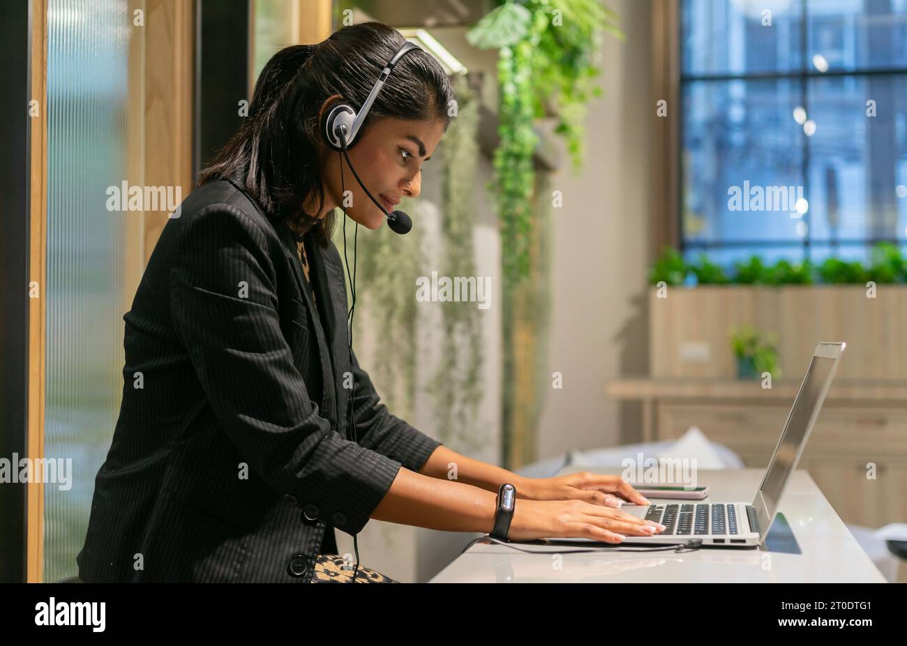 Il servizio clienti parla e aiuta il cliente. Un call center per attività di telemarketing che utilizza cuffie, microfono e computer portatile durante la manutenzione Foto Stock