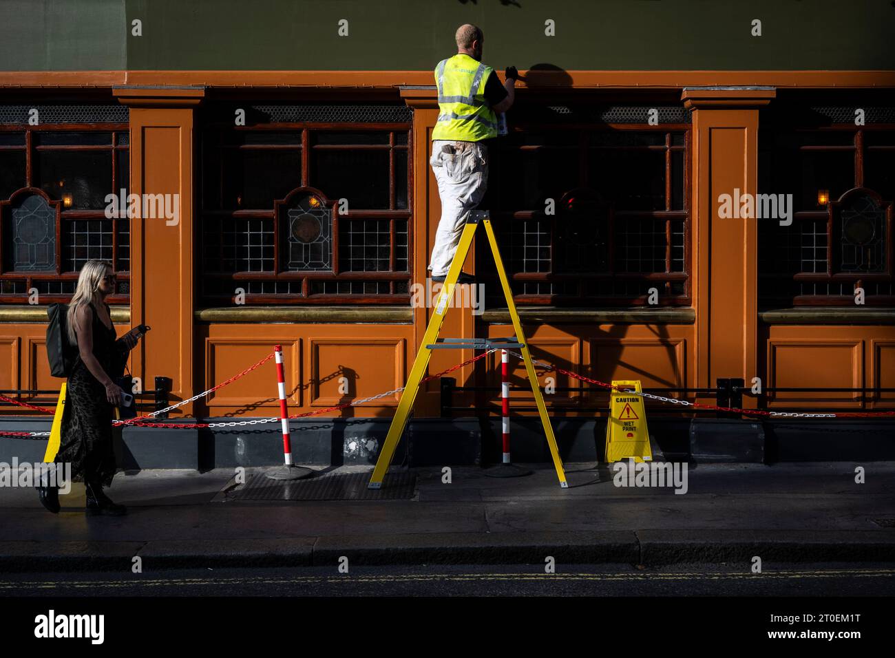 Londra, Regno Unito. 6 ottobre 2023. Meteo del Regno Unito - Un operaio sfrutta il sole pomeridiano e le temperature calde instagionali per dipingere l'esterno del famoso pub Chandos in William IV Street vicino a Trafalgar Square. Le previsioni per il fine settimana sono che il bel tempo continui con sole e temperature di 25C nella capitale. Crediti: Stephen Chung / Alamy Live News Foto Stock