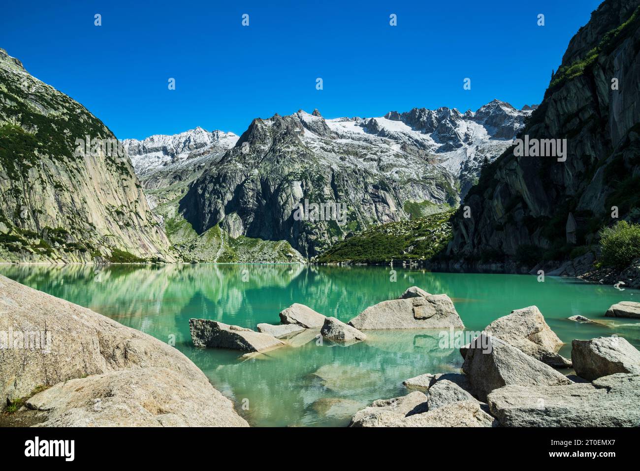 Lago idilliaco circondato da montagne innevate nelle soleggiate giornate estive. Gelmersee, Haslital, Uri Alps, Svizzera, Europa Foto Stock