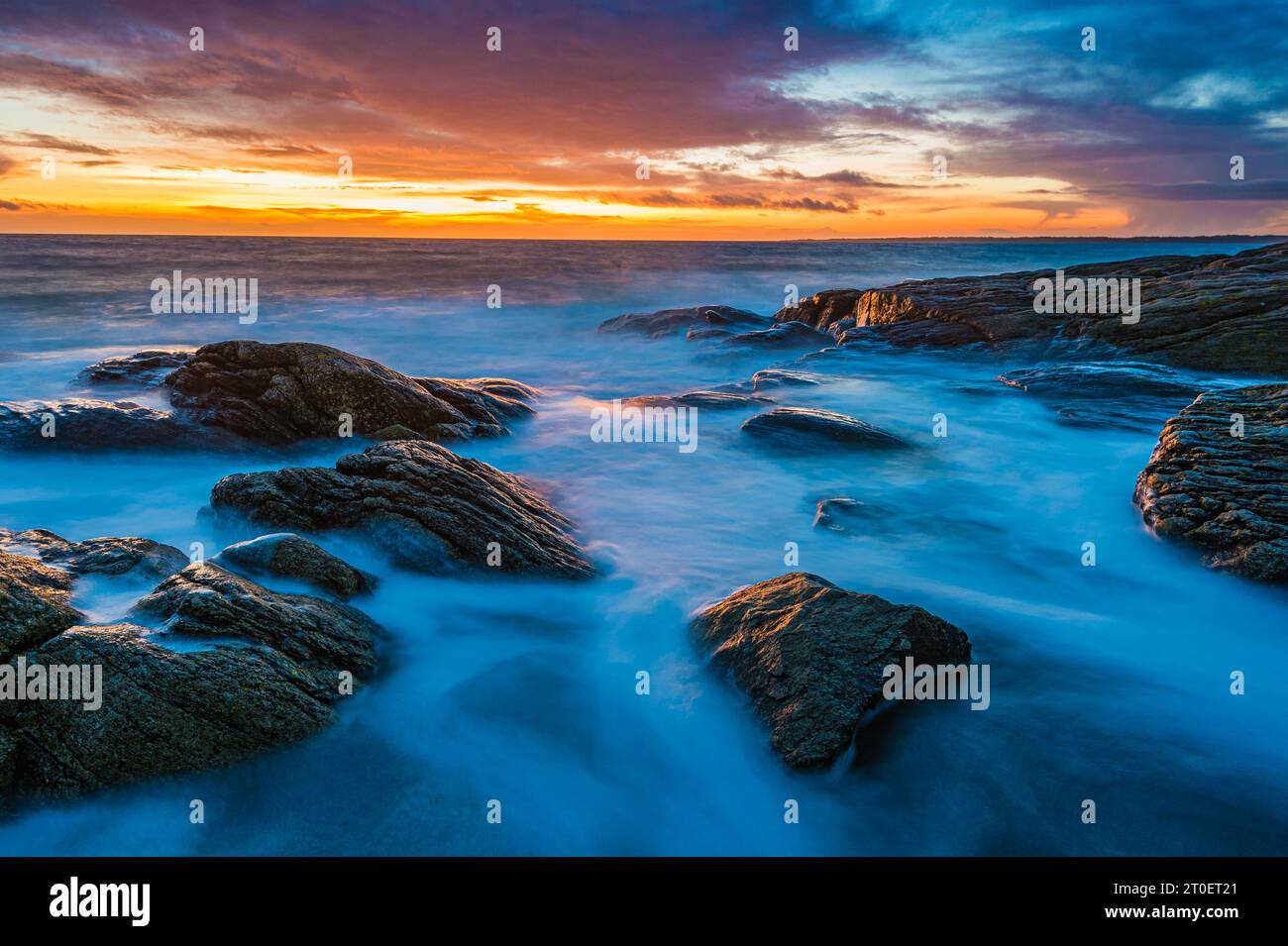 Tranquillo tramonto sulla costa rocciosa della Svezia e sull'oceano calmo. Foto Stock