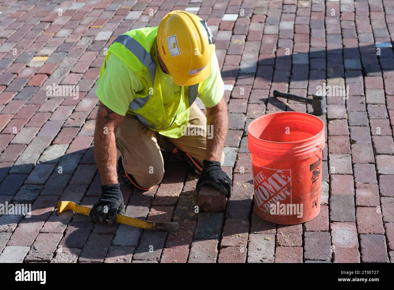 Un lavoratore che sostituisce i mattoni che costeggiano Saginaw Street a Flint, Michigan, USA Foto Stock