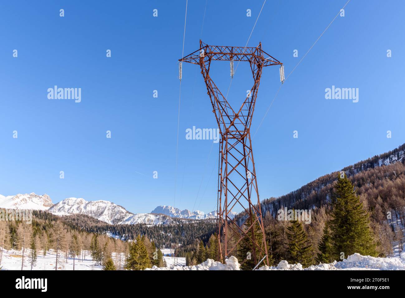 Tralicci elettrici in metallo in un paesaggio innevato di montagna in una chiara giornata invernale Foto Stock