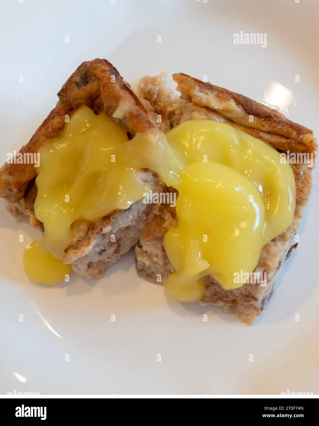 Budino di pane con pane all'uva passa alla cannella, uova, zucchero e latte, quindi cotto al forno. Condita con salsa al limone. USA. Foto Stock