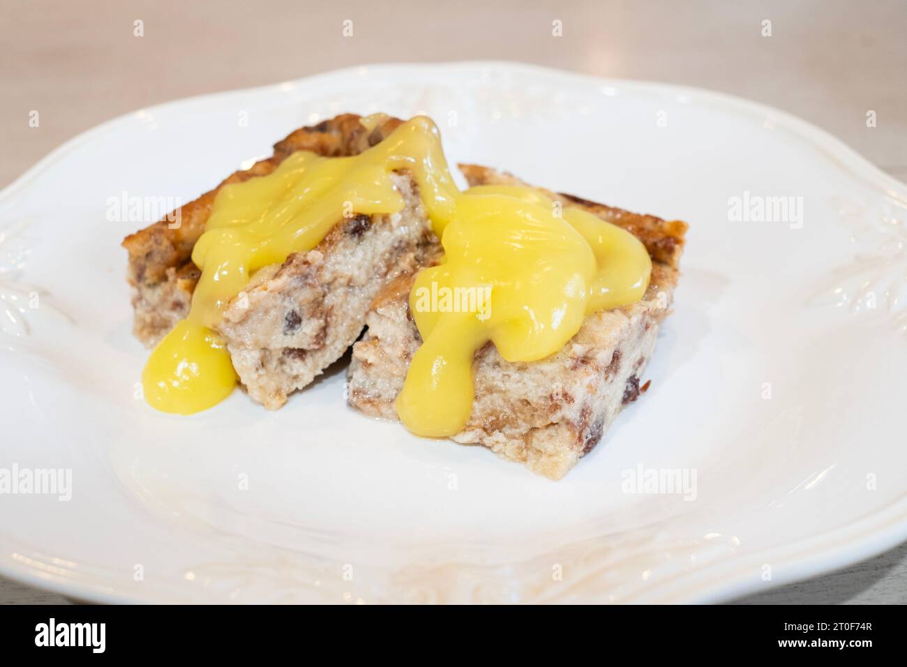 Budino di pane con pane all'uva passa alla cannella, uova, zucchero e latte, quindi cotto al forno. Condita con salsa al limone. USA. Foto Stock