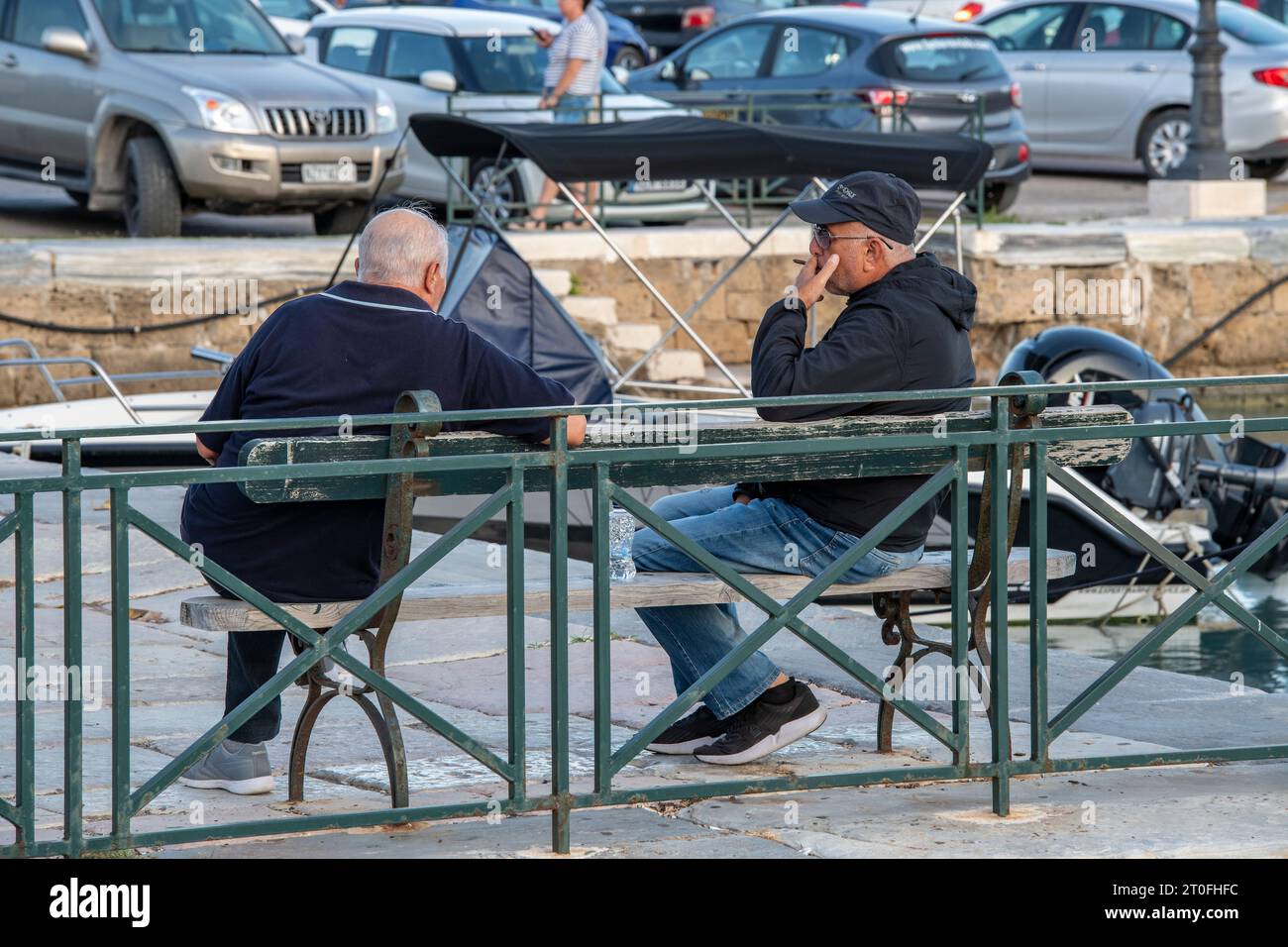 due uomini più anziani o di mezza età seduti su una panchina che chiacchieravano insieme nella città di zante o nella città di zante in grecia. Foto Stock