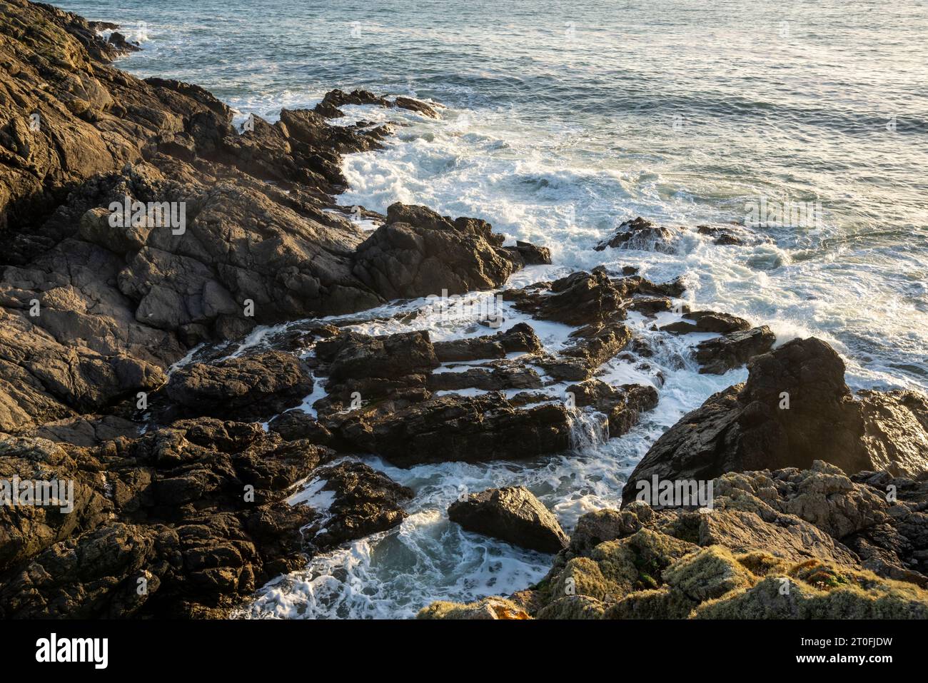 Onde che si infrangono sulle rocce vicino a Rhosneigr sulla costa occidentale di Anglesey, Galles del Nord. Foto Stock
