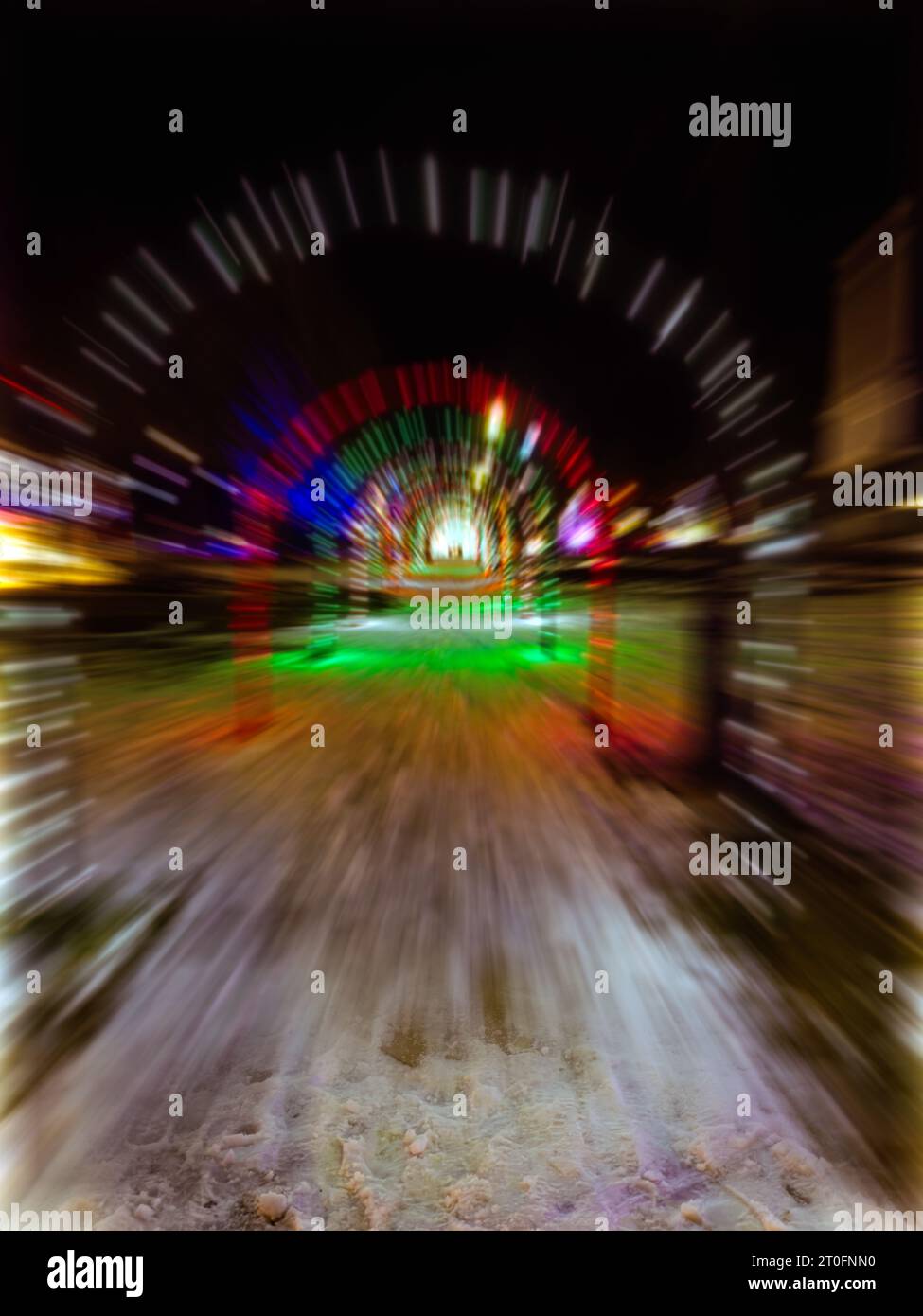Un trattamento astratto di un tunnel natalizio con archi illuminati sopra un passaggio innevato ottenuto con sfocatura radiale Foto Stock