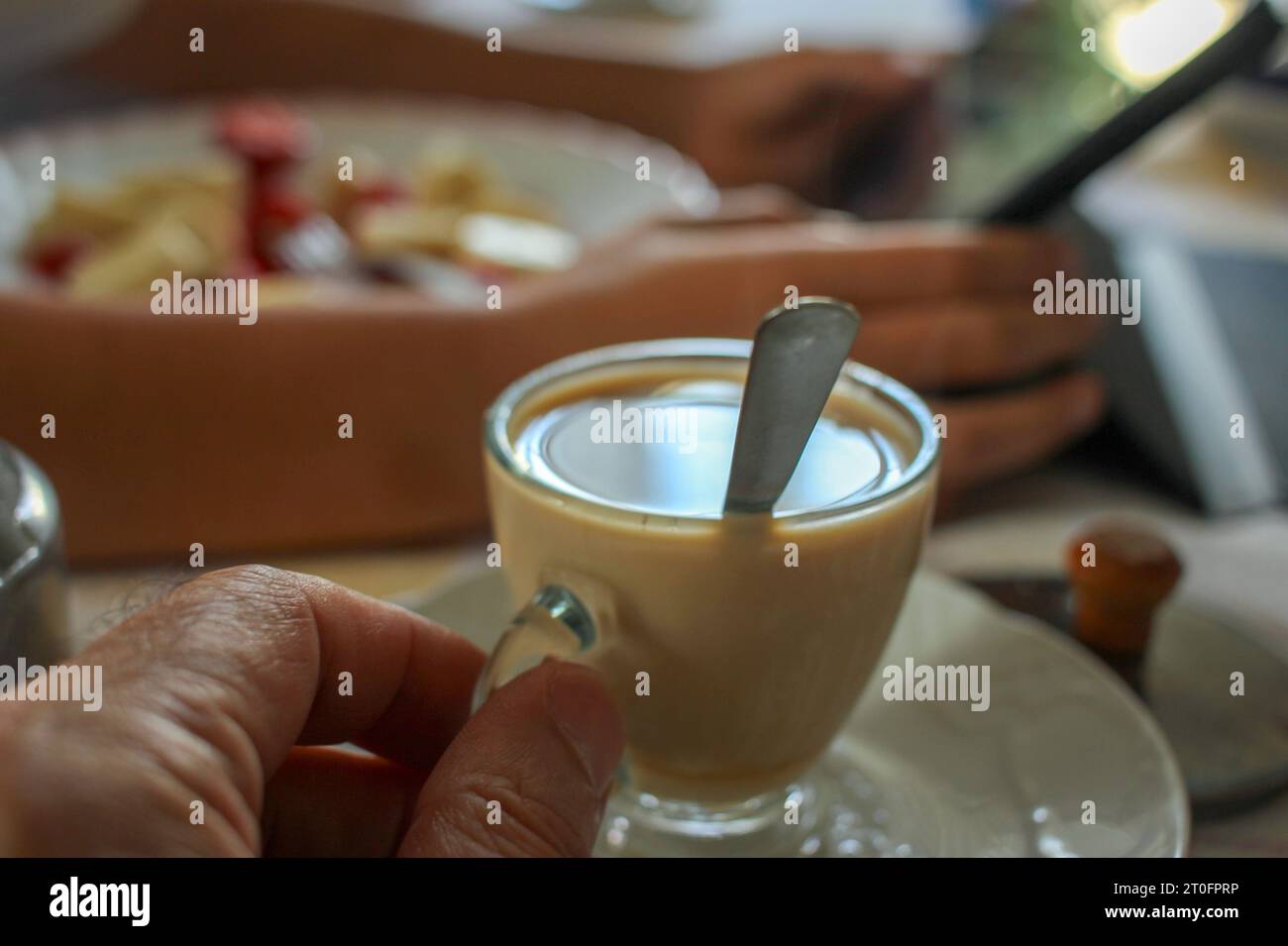 prendere un caffè e guardare un tablet in cucina Foto Stock