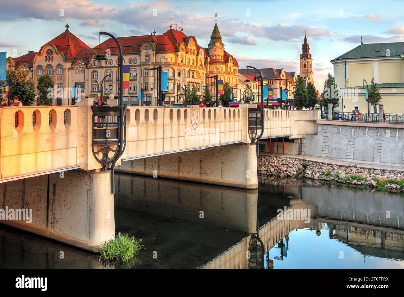 Golden Hour a Oradea, Romania, con il Palazzo dell'Aquila Nera in stile architettonico secessionista che torreggia su un altro ponte in stile art nouveau sul Rapid Cris r Foto Stock