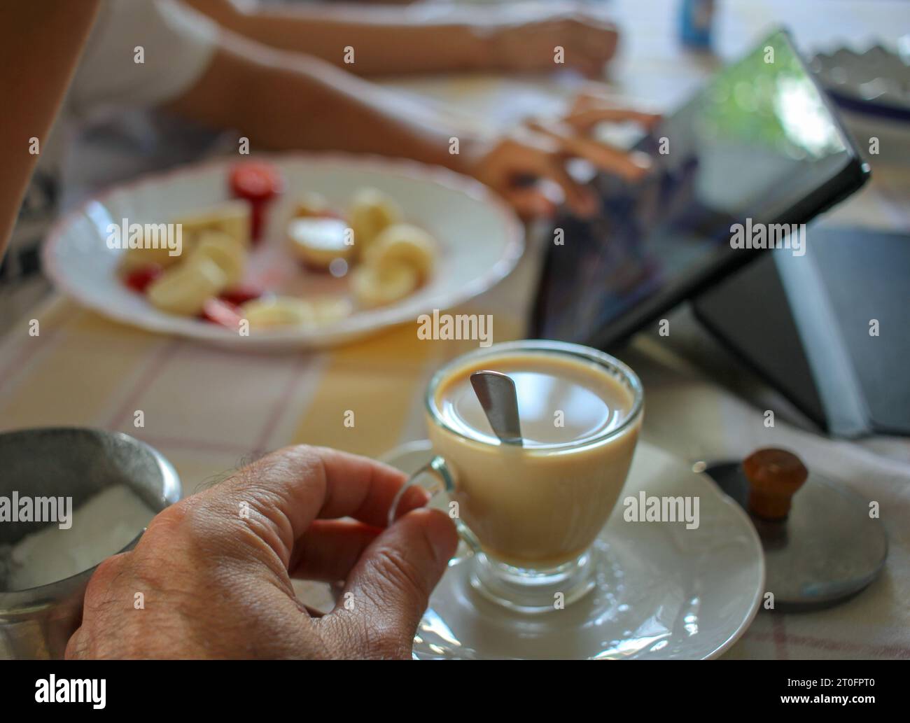 prendere un caffè con latte in compagnia di mio figlio che sta guardando il tablet Foto Stock