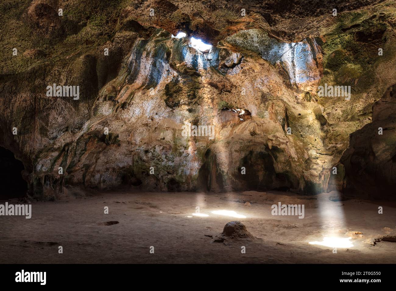 Grotta di Quadiriki nel Parco Nazionale di Arikok, Aruba. I raggi solari si estendono dalle aperture nel tetto della caverna fino al pavimento. Foto Stock