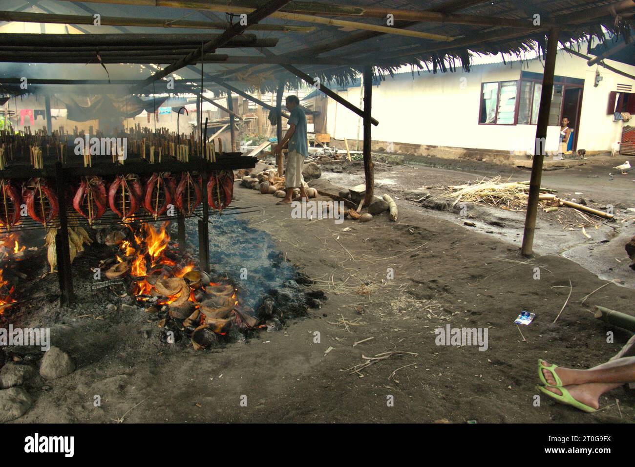 Una produzione di pesce affumicato che utilizza carni di tonno striato in un'industria domestica a Bitung, Sulawesi settentrionale, Indonesia. I contributi delle popolazioni indigene all'innovazione tecnologica offrono un'ampia gamma di opzioni per la gestione, tra l'altro, della sicurezza alimentare, secondo la relazione del 2023 del gruppo intergovernativo sui cambiamenti climatici (IPCC). Popolarmente conosciuto come cakalang fufu, il tonno affumicato è considerato un cibo esotico indigeno, una parte della produzione di tonno striato che è una delle attività economiche più importanti nell'area di Bitung City, uno degli anelli esterni dell'Indonesia di... Foto Stock
