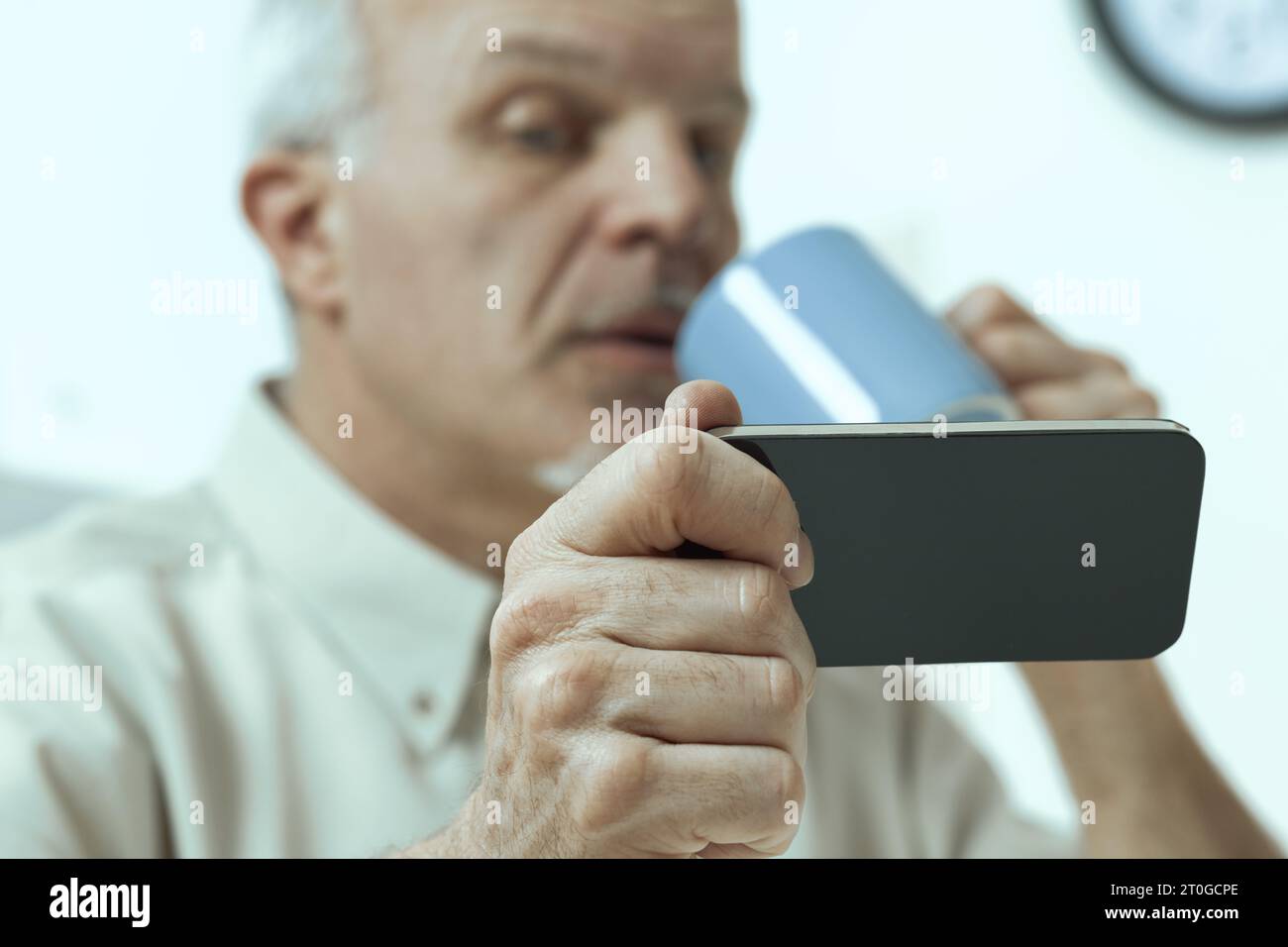 signore anziano, durante i pasti e le pause, consulta smartphone, tablet. La sua generazione rispetta, non sottovaluta, la tecnologia. Ma discernente credibl Foto Stock