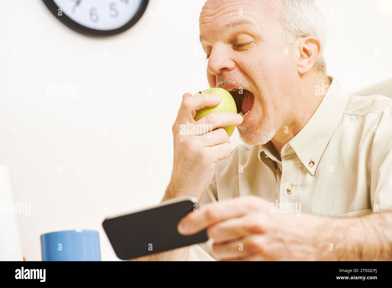 L'attenzione è su una mela verde. Poiché l'anziano praticante gode di ogni goccia delle sue vitamine nella sua cucina, ricorda il proverbio e il suo impegno Foto Stock