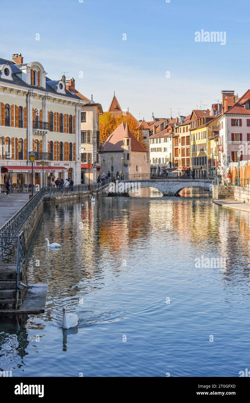 Vista sul fiume Thiou verso la città e gli edifici di Annecy, Francia, con il Pont Perrière (ponte) sullo sfondo Foto Stock