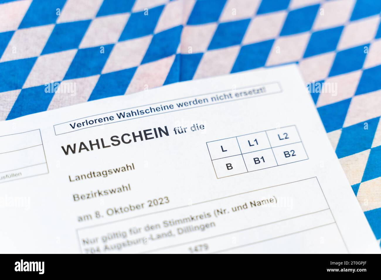 Augusta, Baviera, Germania - 29 settembre 2023: Scheda elettorale per le elezioni statali e distrettuali in Baviera su bandiera bavarese *** Wahlschein zur Landtagswahl und Bezirkswahl in Bayern auf einer bayerischen Flagge Foto Stock