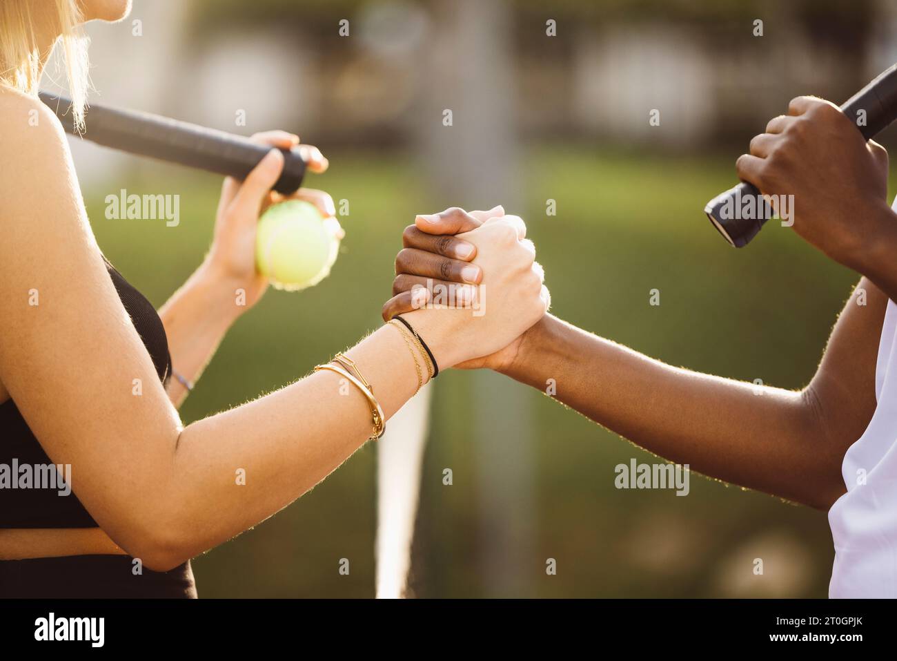 Giocatori di tennis amatoriali che stringono la mano alla rete. Due donne sportive che stringono le mani sulla rete dopo la partita. Foto Stock