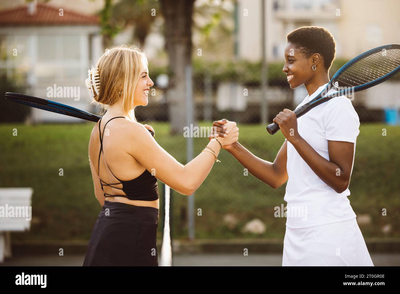 Giocatori di tennis amatoriali che stringono la mano alla rete. Due donne sportive che stringono le mani sulla rete dopo la partita. Foto Stock