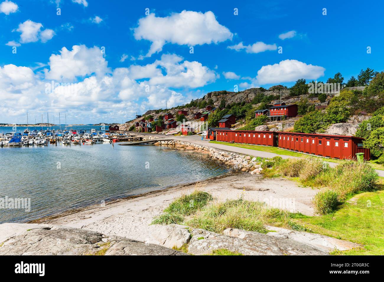 Il paesaggio costiero della città portuale con una fila di case rosse sulla spiaggia e un cielo blu. Foto Stock