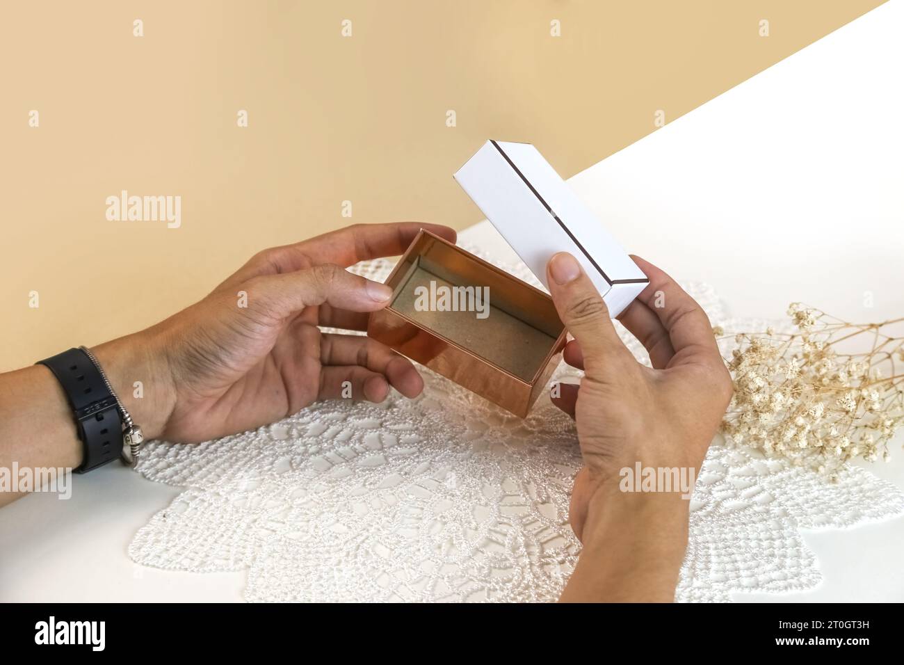 Mani maschili che aprono una elegante confezione regalo vuota. Mockup presenta una confezione regalo su sfondo chiaro Foto Stock
