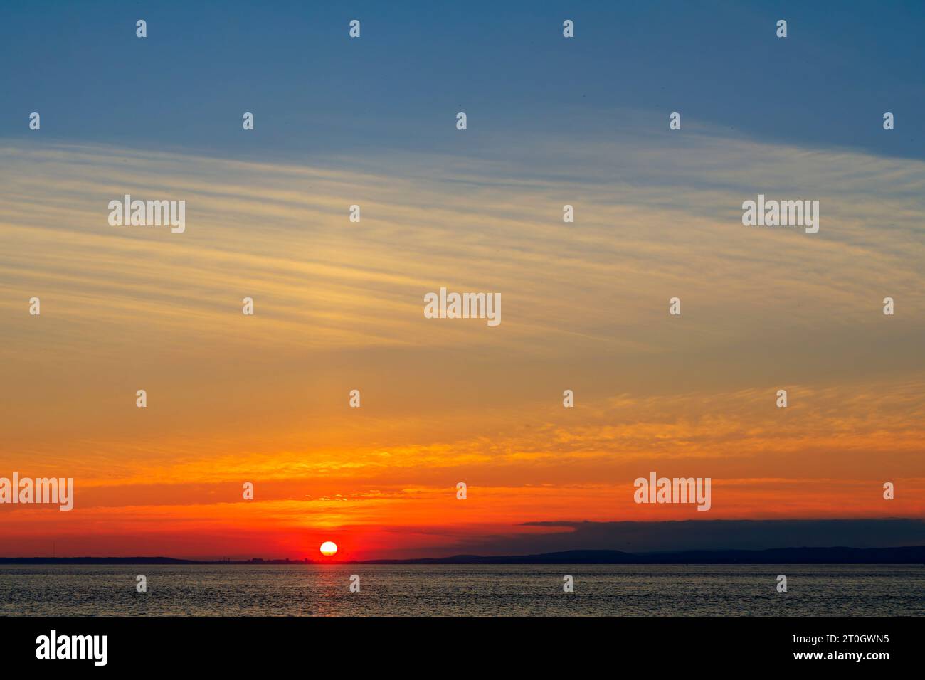 Il sole che tramonta illumina la nuvola lungo la costa gallese Foto Stock