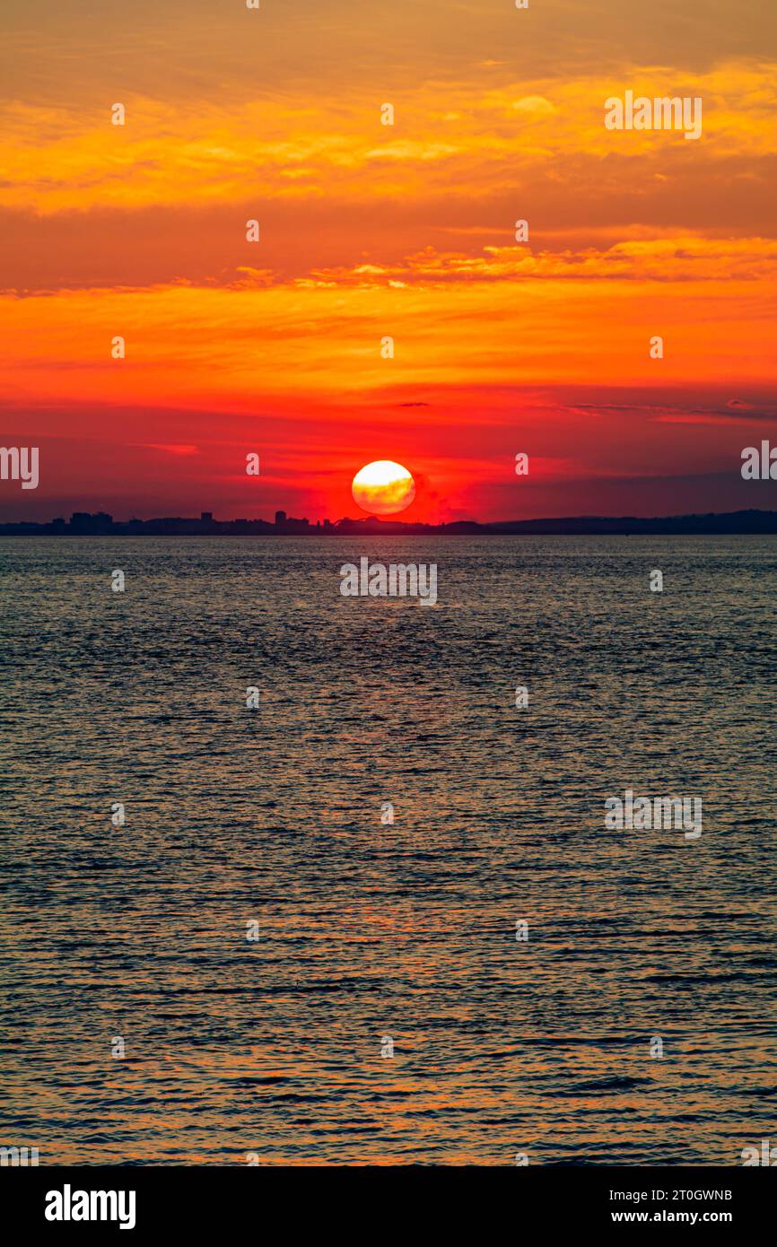 Il sole che tramonta illumina la nuvola lungo la costa gallese Foto Stock